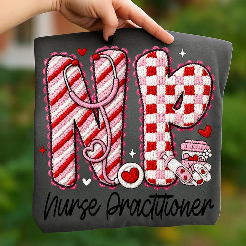 May include: A dark gray t-shirt featuring the letters "NP" in a red and white design, with a stethoscope and hearts. The words "Nurse Practitioner" are printed below the letters. The design is surrounded by a pink scalloped border.