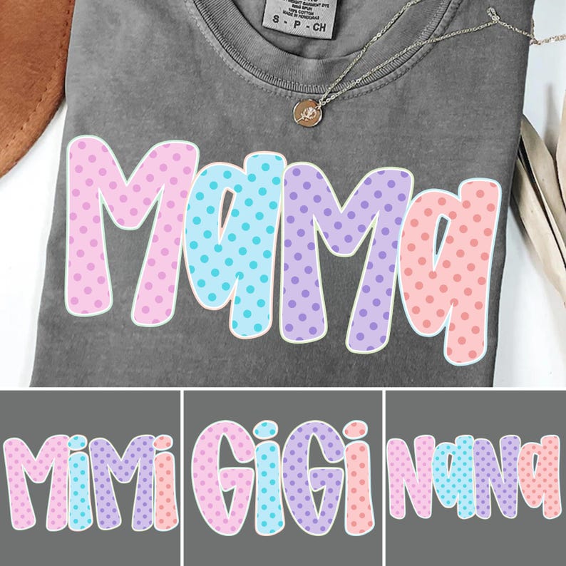 Puede incluir: Una camiseta gris con la palabra "Mama" en letras grandes y coloridas con lunares. Las letras est&aacute;n delineadas en blanco y presentan lunares rosas, azules y morados. Se ve un collar plateado con un peque&ntilde;o colgante.