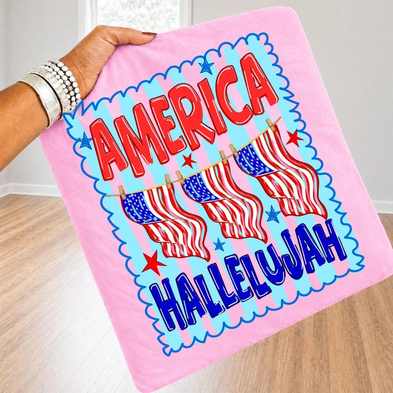 Puede incluir: Un art&iacute;culo de tela cuadrado de color rosa claro con un estampado gr&aacute;fico que incluye el texto AMERICA en rojo y HALLELUJAH en azul. El dise&ntilde;o muestra tres banderas estadounidenses colgadas de un tendedero, rodeadas por un borde festoneado azul y estrellas rojas.