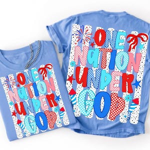 Pu&ograve; includere: Due magliette azzurre con una stampa grafica che riporta il testo ONE NATION UNDER GOD in motivi rossi, bianchi e blu. Il design include fuochi d'artificio, stelle e un fiocco rosso su uno sfondo di pois verticali neri e bianchi.