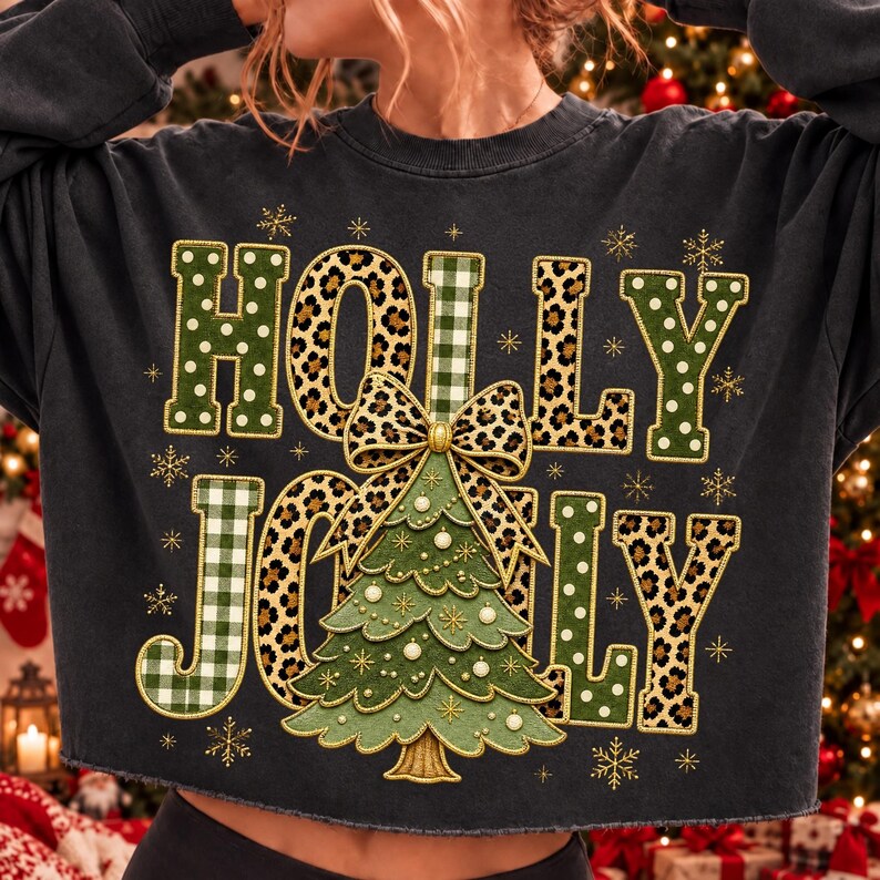 May include: A charcoal gray long-sleeve sweatshirt featuring the text HOLLY JOLLY in a mix of green polka dot, leopard print, and green gingham patterns. A central graphic shows a green Christmas tree topped with a large leopard print bow.