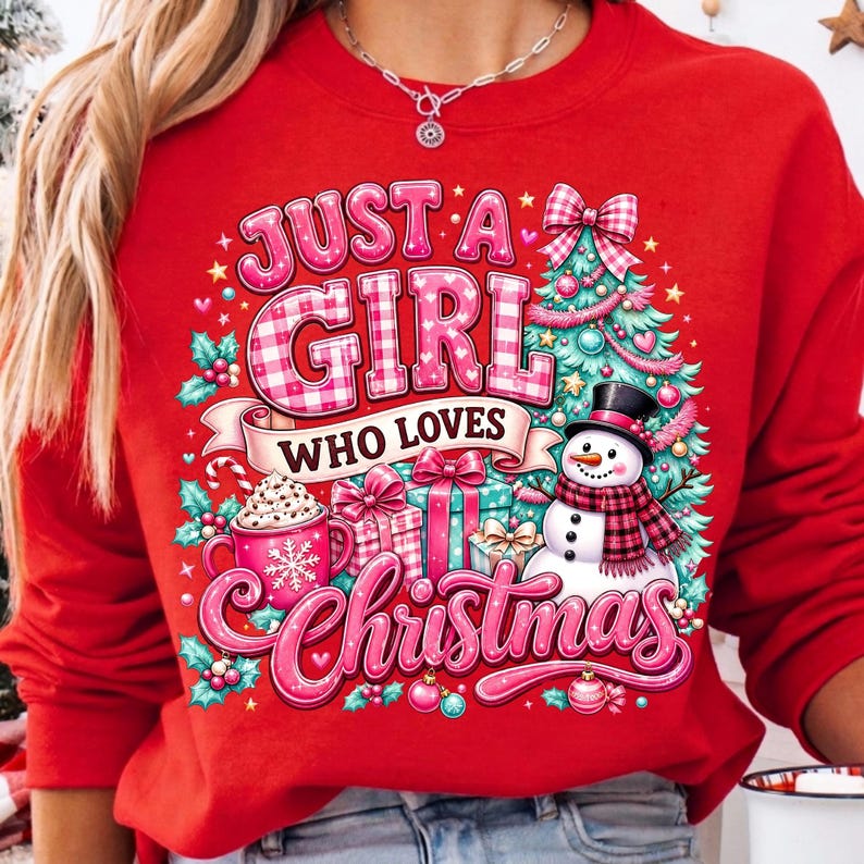 May include: A bright red sweatshirt featuring a festive graphic with the text "JUST A GIRL WHO LOVES CHRISTMAS". The design includes a decorated Christmas tree, a snowman with a plaid scarf, wrapped gift boxes, and a mug of hot cocoa.