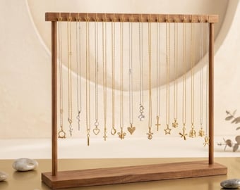 May include: A wooden jewelry display stand with multiple necklaces hanging from it. The necklaces have various pendant shapes, including hearts, stars, and crosses. The stand is made of dark wood and has a rectangular base.