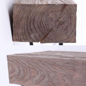 May include: A rustic wooden bench with a dark brown finish. The bench features a thick, rectangular wooden top with visible wood grain and a crack. It is supported by black metal legs, creating a contrast in textures and colors.