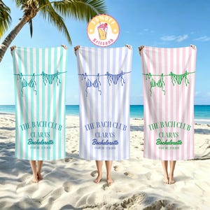 May include: Three rectangular beach towels featuring vertical stripes in light blue, light purple, and light pink. Each towel displays a green line drawing of two bikinis, the text THE BACH CLUB, CLARA'S Bachelorette, and OAHU HI | FEB 2026.