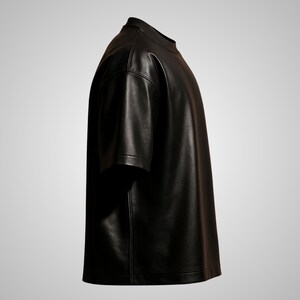 May include: A black leather t-shirt with short sleeves. The shirt has a crew neck and a straight hem. The material appears to be smooth and shiny, with visible stitching along the seams. The shirt is displayed against a neutral background.