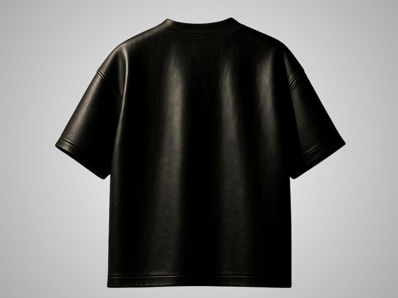 May include: A black, short-sleeved t-shirt made of a leather-like material. The shirt has a crew neck and a relaxed fit. The image shows the back of the shirt, highlighting its smooth texture and simple design. The garment is suitable for casual wear.