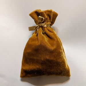 May include: A small, golden velvet pouch with a gold ribbon tied around the top.