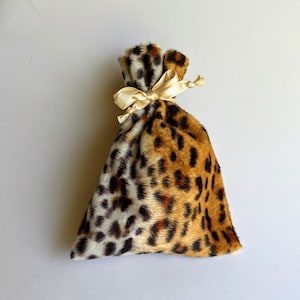 May include: A small, leopard print drawstring bag with a cream-colored ribbon tied around the top.