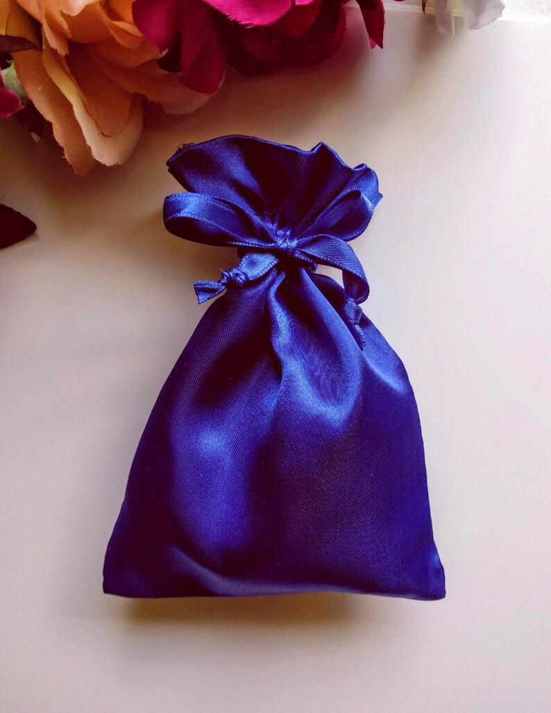 May include: A small, royal blue satin drawstring bag with a matching ribbon tied in a bow.