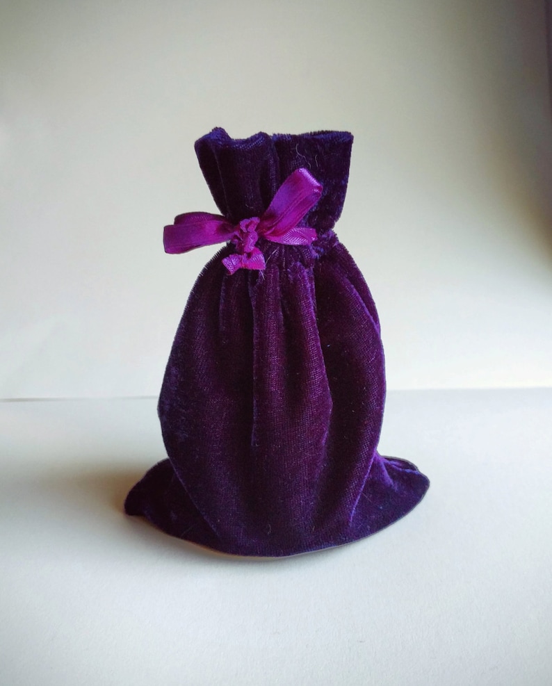 May include: A small purple velvet bag with a purple ribbon tied around the top.