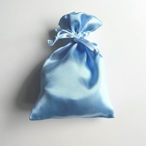 May include: A light blue satin drawstring bag. The bag is tied with a matching ribbon.