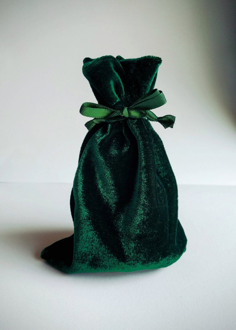 May include: A dark green velvet pouch with a green satin ribbon tied around the top.