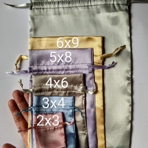 May include: Set of 6 satin drawstring bags in various sizes and colors, including green, gold, purple, brown, blue, and pink. The bags are labeled with their dimensions: 8x13, 6x9, 5x8, 4x6, 3x4, and 2x3.
