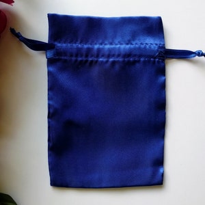 May include: A small, royal blue satin drawstring bag. The bag is empty and has a white background.