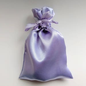 May include: A lavender satin drawstring bag with a tied ribbon.
