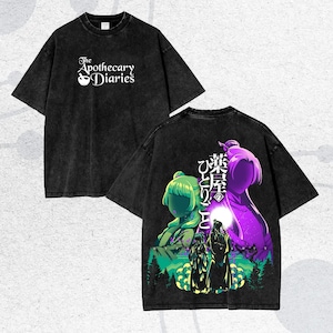 May include: Black t-shirt with the text "The Apothecary Diaries" and a mortar and pestle graphic. The back of the shirt features a colorful anime-style illustration with Japanese text and figures in green and purple.