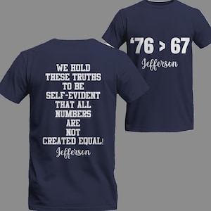 May include: Navy blue t-shirts with white text. One shirt displays "'76 > 67 Jefferson" on the front. The other shirt shows "WE HOLD THESE TRUTHS TO BE SELF-EVIDENT THAT ALL NUMBERS ARE NOT CREATED EQUAL! Jefferson" on the back.