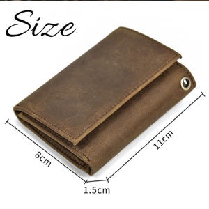May include: A brown leather wallet with a worn, textured appearance. The wallet is 11 cm long, 8 cm wide, and 1.5 cm thick. It has a metal eyelet and a folded design. The word "Size" is written in a cursive font.