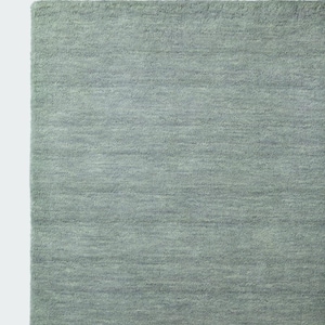 May include: A rectangular area rug in a solid sage green colour. The rug features a dense, short-pile texture with subtle horizontal variations in the weave, creating a soft, uniform appearance across the entire surface of the floor covering.