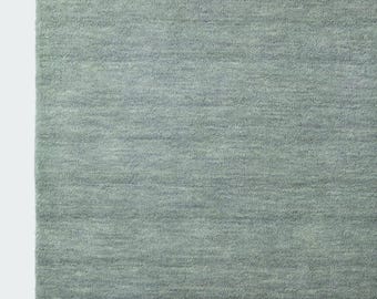 May include: A rectangular area rug in a solid sage green color. The rug features a dense, short-pile texture with subtle horizontal variations in the weave, creating a soft, uniform appearance across the entire surface of the floor covering.