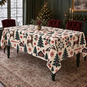 May include: A rectangular tablecloth with a cream-coloured base featuring a repeating pattern of brown reindeer, green pine trees, small red cabins, red snowflakes, and red berries. The design is printed across the entire fabric surface.