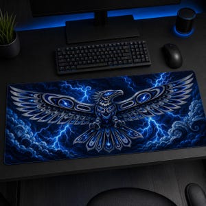 May include: A rectangular desk mat featuring a stylised eagle with silver and blue tribal-inspired patterns. The bird is centred against a dark background filled with swirling blue clouds and bright, jagged lightning bolts across the entire surface.