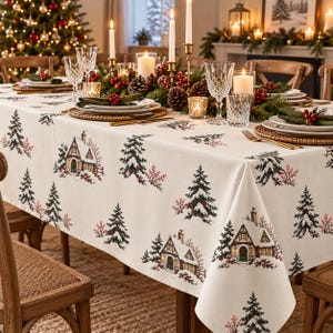 Puede incluir: Un mantel rectangular blanco con un patrón repetitivo de abetos cubiertos de nieve, pequeñas casas con ventanas iluminadas y ramas de bayas rojas. La tela cubre una mesa de comedor dispuesta con platos, vasos y velas.