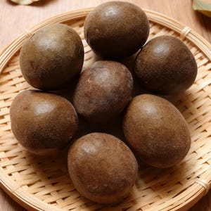 May include: A close-up shot of seven brown, oval-shaped lo han guo fruits arranged in a woven bamboo basket. The fruits have a slightly textured surface and are a rich, dark brown color. The basket is light brown.