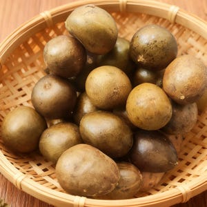 May include: A woven basket filled with numerous brown, round fruits. The fruits have a slightly textured surface and vary in shades of brown, from light tan to darker hues. The basket is made of light-colored woven material.