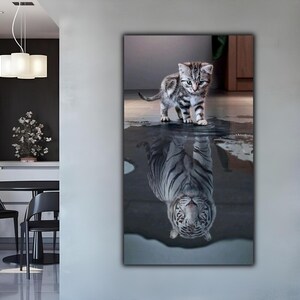 Può includere: Stampa su tela raffigurante un gattino a strisce in piedi nell'acqua, con il suo riflesso che appare come una tigre bianca. L'opera d'arte è esposta su una parete in un ambiente interno moderno, con un tavolo da pranzo e sedie visibili.
