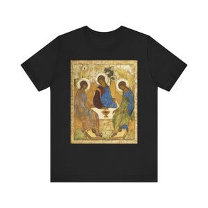 Könnte beinhalten: Schwarzes T-Shirt mit einem religiösen Ikonen-Druck. Das Kunstwerk zeigt drei Figuren in Gewändern, die um einen Tisch sitzen. Die Figuren sind in Blau-, Rot- und Grüntönen gehalten, vor einem gold-beigen Hintergrund.