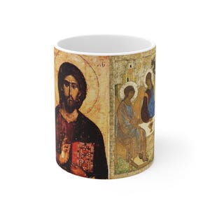 May include: A white ceramic coffee mug featuring religious artwork. The mug displays a detailed illustration of a religious figure with a halo, and another scene with figures. The artwork is in warm, earthy tones.