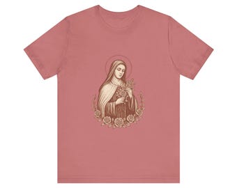 Puede incluir: Camiseta rosa polvoriento con una ilustración en tonos sepia de una mujer sosteniendo rosas, rodeada por una corona floral. La obra de arte tiene una estética vintage, con un halo sobre la cabeza de la mujer.