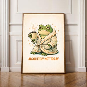 May include: A framed art print featuring a cartoon frog in a white robe, holding a coffee mug. The frog has a grumpy expression. The text "ABSOLUTELY NOT TODAY" is printed below the frog.