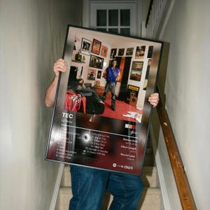 May include: A framed rectangular poster featuring the album cover for TEC by Lil Tecca. The design includes a photograph of a person in a room, a tracklist with 17 songs, the release date of Jan 13, 2024, an album length of 40:10, and the label Galactic.