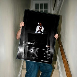 May include: A framed poster with the title "XTENDED" by Ken Carson. The poster features a black and white image of a person and a list of song titles. The release date is October 2022, with an album length of 61:47.