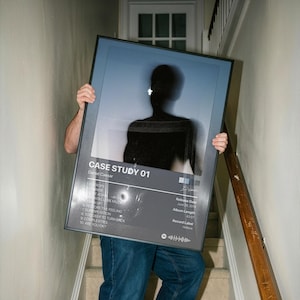May include: A rectangular framed poster featuring the Case Study 01 album cover by Daniel Caesar. The design includes a dark silhouette of a person, a tracklist with ten songs, release date June 28, 2019, album length 43:07, and a Spotify code.
