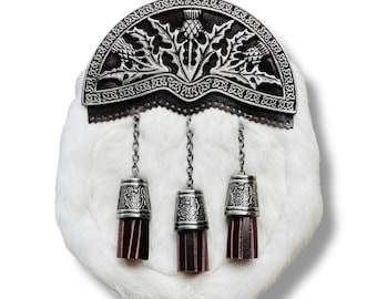 Può includere: Un sporran in pelliccia bianca con un cantle decorativo in metallo argentato con disegni di cardi. Tre nappe in metallo argentato con accenti in pelle bordeaux pendono dallo sporran, collegate da catene. Un accessorio scozzese tradizionale.