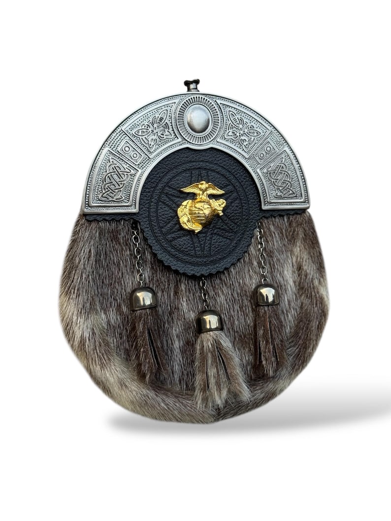 K&ouml;nnte beinhalten: Ein traditioneller schottischer Sporran mit silbernem Cantle und Fellk&ouml;rper. Der Cantle weist komplizierte keltische Knotenmuster und ein zentrales Emblem auf. Drei Quasten h&auml;ngen von unten und tragen zur dekorativen Ausstrahlung des Sporrans bei.