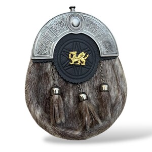 K&ouml;nnte beinhalten: Eine traditionelle schottische Sporran mit silbernem Cantle und Fellk&ouml;rper. Die schwarze Lederfront zeigt ein goldenes Drachenemblem. Drei Quasten h&auml;ngen von unten, und Ketten verbinden die Quasten mit dem Cantle.