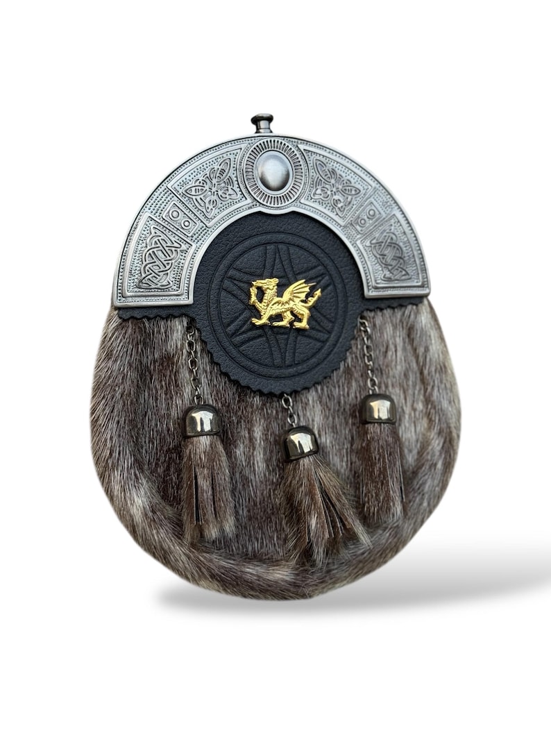 K&ouml;nnte beinhalten: Eine traditionelle schottische Sporran mit silbernem Cantle und Fellk&ouml;rper. Die schwarze Lederfront zeigt ein goldenes Drachenemblem. Drei Quasten h&auml;ngen von unten, und Ketten verbinden die Quasten mit dem Cantle.