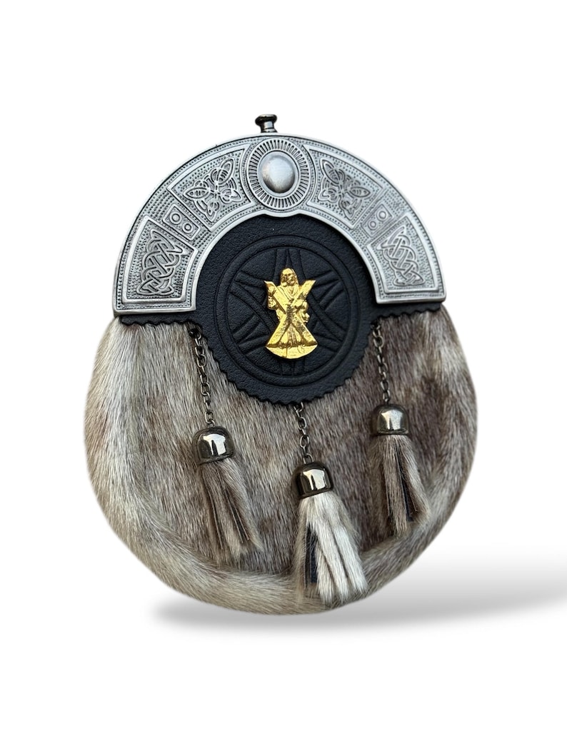 K&ouml;nnte beinhalten: Eine traditionelle schottische Sporran mit einem silbernen Cantle mit keltischen Knotenmustern und einem zentralen Emblem. Die Sporran hat einen Pelzk&ouml;rper, eine schwarze Lederfront und drei silberne Quastenanh&auml;nger.
