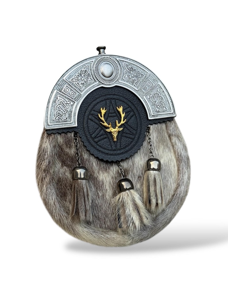 K&ouml;nnte beinhalten: Ein traditioneller schottischer Sporran mit silbernem Cantle und einer schwarzen Lederklappe mit einem goldenen Hirsch-Emblem. Der Sporran hat einen Pelzk&ouml;rper und drei dekorative Quasten.