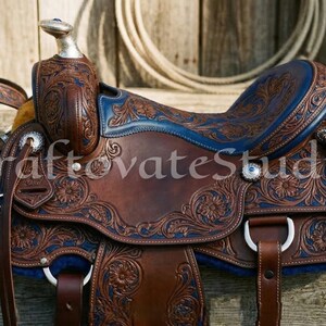 Könnte beinhalten: Ein brauner Westernsattel aus Leder mit aufwendigen floralen Verzierungen und blauen Akzenten. Der Sattel verfügt über silberfarbene Beschläge und einen passenden Zaum. Das Bild enthält den Text "CraftovateStudio".