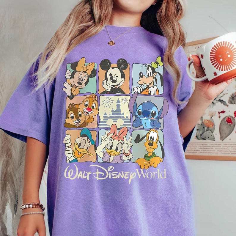 Puede incluir: Camiseta morada con un dise&ntilde;o de cuadr&iacute;cula con personajes de Disney, incluyendo Mickey Mouse, Minnie Mouse, Goofy, Donald, Daisy, Chip y Chop, Stitch y Pluto. El texto "Walt Disney World" est&aacute; impreso debajo.