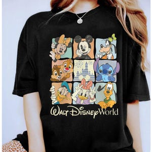 Puede incluir: Camiseta negra con una cuadr&iacute;cula de personajes de Disney, incluyendo Mickey y Minnie Mouse, Goofy, Donald y Daisy Duck, Chip y Chop y Stitch. Las palabras "Walt Disney World" est&aacute;n impresas en amarillo.