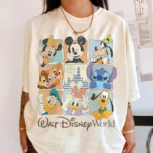 Puede incluir: Camiseta color crema con una cuadr&iacute;cula de personajes de Disney, incluyendo Mickey Mouse, Minnie Mouse, Goofy, Donald Duck, Daisy Duck, Chip y Chop, Stitch y Pluto. Las palabras "Walt Disney World" est&aacute;n impresas en la parte inferior.