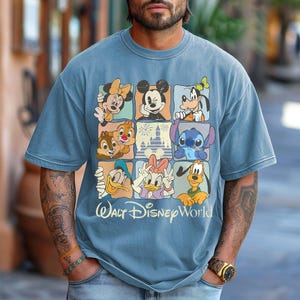 Puede incluir: Camiseta azul claro de manga corta con una cuadr&iacute;cula de personajes de Disney, incluyendo Mickey Mouse, Minnie Mouse, Goofy, Donald, Daisy, Chip y Chop, Stitch y Pluto. Las palabras "Walt Disney World" est&aacute;n impresas en blanco debajo.