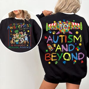 May include: Black sweatshirt with colorful text and graphics promoting autism awareness. The front features the words "Autism Awareness" and a group of cartoon characters. The back says "Autism and Beyond" with a rocket ship and puzzle pieces.